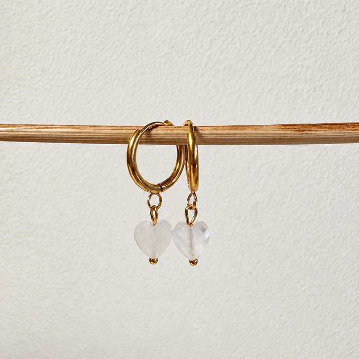 Goldene Creolen aus hypoallergenem Edelstahl mit herzförmigen Bergkristalle-Anhängern – handgemachter Schmuck von Miwi Jewels.